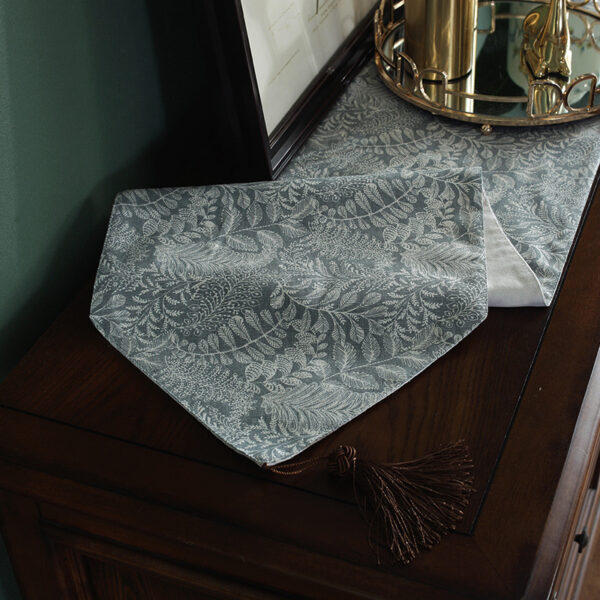 Gray floral table runner on a console table, showing tassel detail on the end