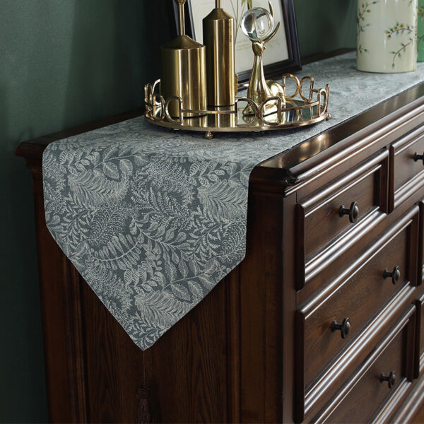 Gray vintage floral table runner on a wooden dresser, styled with decor pieces