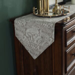 aLight coffee floral table runner styled on a dark wood console table with gold decor