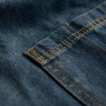 Vintage denim barista apron fabric close-up with contrast stitching