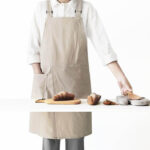 Off White Adjustable Strap Shoulder Apron cotton linen split front apron worn by model during home bread baking