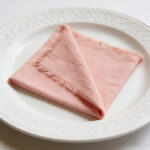 blush pink cotton fringe napkin folded on white plate, romantic table decor