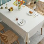 stain resistant tablecloths Waterproof, solid off white cotton linen waterproof tablecloth laid on indoor rectangular dining table, farmhouse home decor