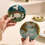 handmade wool felt coaster save the earth and spring prairie designs held in hands