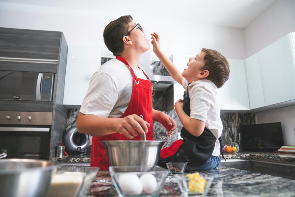Two brothers cooking together in a modern kitchen, enjoying playful moments.