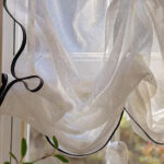 French Linen Cafe Curtain fabric close-up shot, vintage cream semi sheer linen texture, black edge trim detail, light filtering breathable material