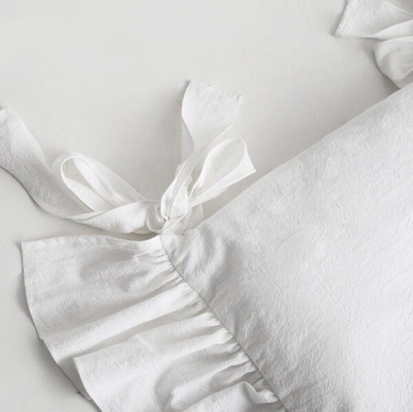 white dining chair seat cover with ruffled hem and bow tie strap detail, soft fabric farmhouse chair seat protector close-up