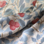 close up fabric texture of cottage blackout curtain panel, vintage blue and red berry botanical print on off-white fabric