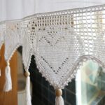 close‑up of crochet heart lace hem with hanging tassels on white tie‑top window valance