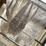 Close‑up texture of flower embroidery on sheer lace curtain material