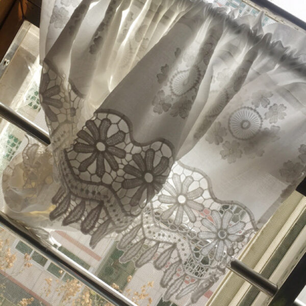 Close‑up texture of flower embroidery on sheer lace curtain material