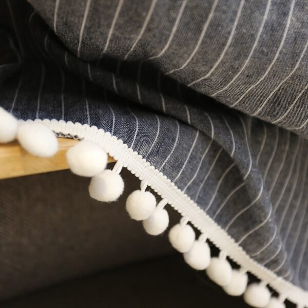 Close‑‑up shot of white pom‑pom hem and fine stripe texture of cotton‑blend tier curtain
