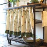 Country‑style kitchen interior decorated with botanical print tier curtains