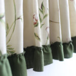 Close‑up view of green ruffle hem and floral print on linen blend tier curtain