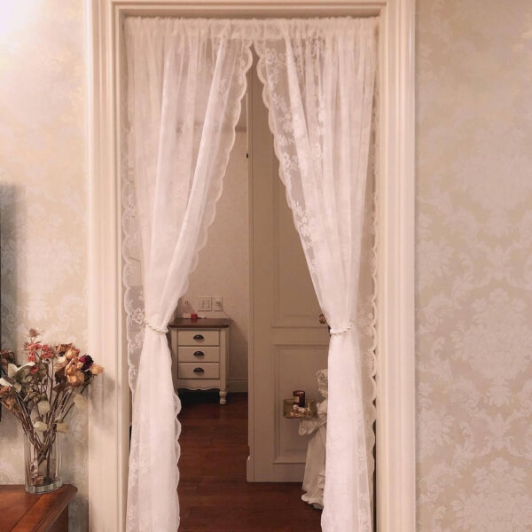 White lace sheer doorway curtain hanging open on interior door frame