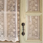 Subtle woven texture on white sheer fabric of door curtain with green top trim