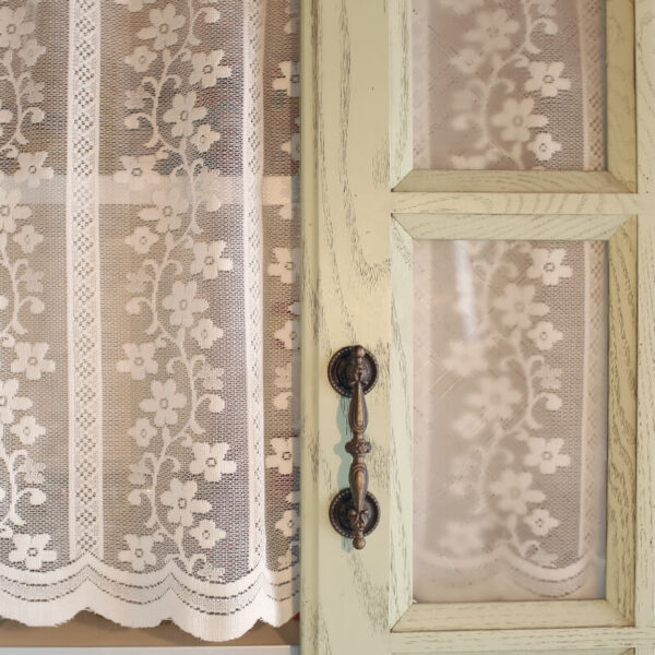 Subtle woven texture on white sheer fabric of door curtain with green top trim