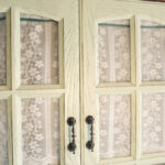 White semi‑transparent sheer door curtain with green trim hanging over wooden entry doorway