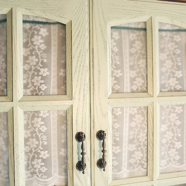 White semi‑transparent sheer door curtain with green trim hanging over wooden entry doorway