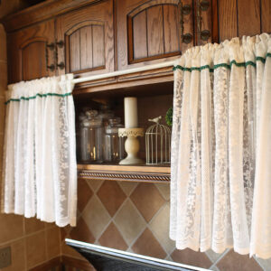 White sheer door curtain with dark‑green trim, rod‑pocket semi‑transparent pantry curtain hanging over kitchen cabinet opening