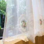 Semi‑transparent sheer fabric of embroidered cafe curtain, light passing through sheer material