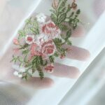 Macro close‑up, delicate oval rose flower embroidery on sheer curtain fabric