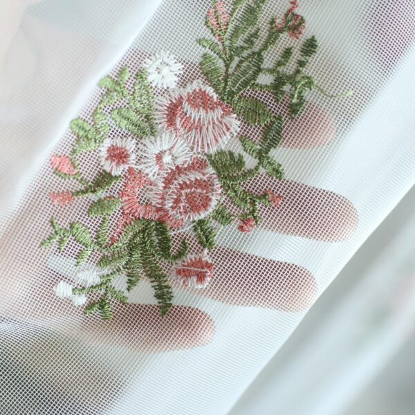 Macro close‑up, delicate oval rose flower embroidery on sheer curtain fabric
