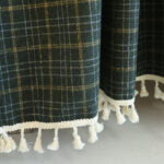 Close‑up view of british vintage plaid tier curtain thick yarn‑blend fabric and white tassel fringe hem