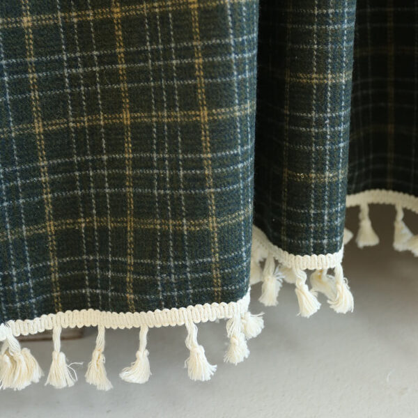 Close‑up view of british vintage plaid tier curtain thick yarn‑blend fabric and white tassel fringe hem