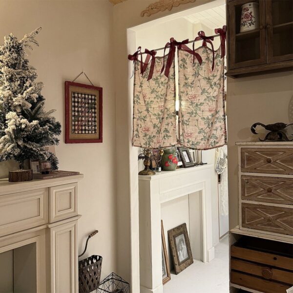 Soft rose print tie‑top curtain hanging on interior doorway, warm cottage‑style home decoration