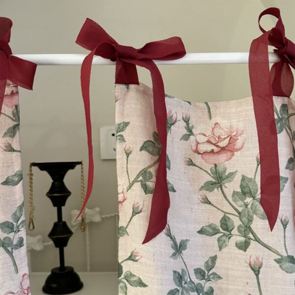 Close‑up view of cottage rose tie‑top curtain, burgundy bow tie detail, linen‑look floral fabric