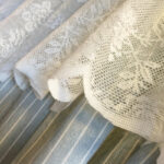 Close‑up of lace top and striped fabric on blue striped doorway curtain