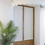 white dual rod pocket curtain decor on wooden doorway with houseplant