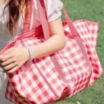 Picnic tote convertible blanket carried over shoulder, red‑white check pattern