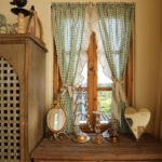 Green gingham cafe curtain hanging on wooden window, cottage home interior view