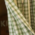 Green white plaid farmhouse cafe curtain fabric close-up with lace trim, 60 polyester 40 cotton texture