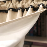 Close‑up of black pom‑pom hem on modern semi‑blackout short curtain single panel