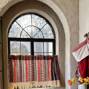 Bohemian geometric tier curtain hung on arched kitchen window, vintage boho home decor