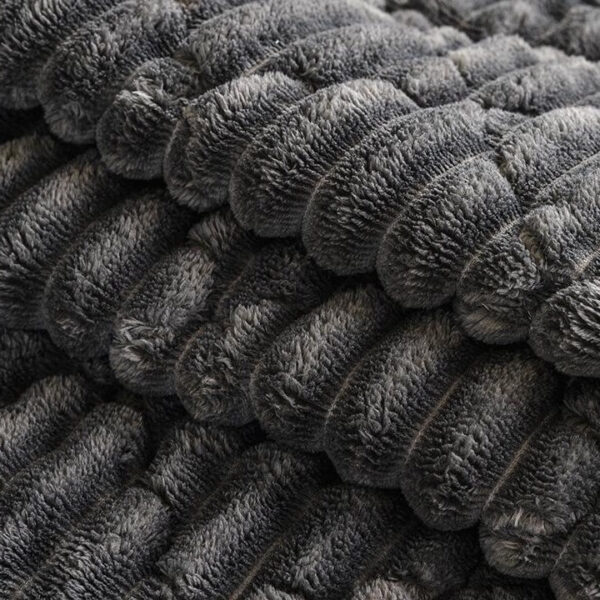 Close‑up view of thick plush textured fabric of sofa throw cover, cozy quilted surface
