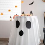 White Halloween ghost print round tablecloth styled on dessert table with pumpkin hanging banner